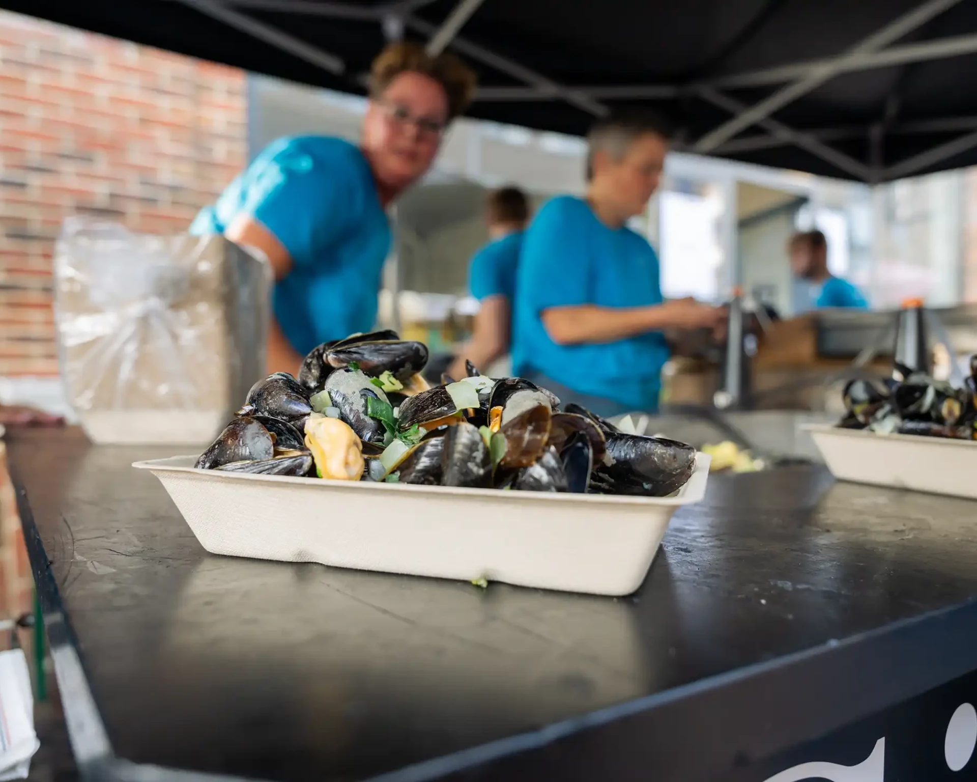 Bakjes met verse mosselen op de bar tijdens het Zeister Mosselfestival, klaar om geserveerd te worden aan festivalbezoekers.