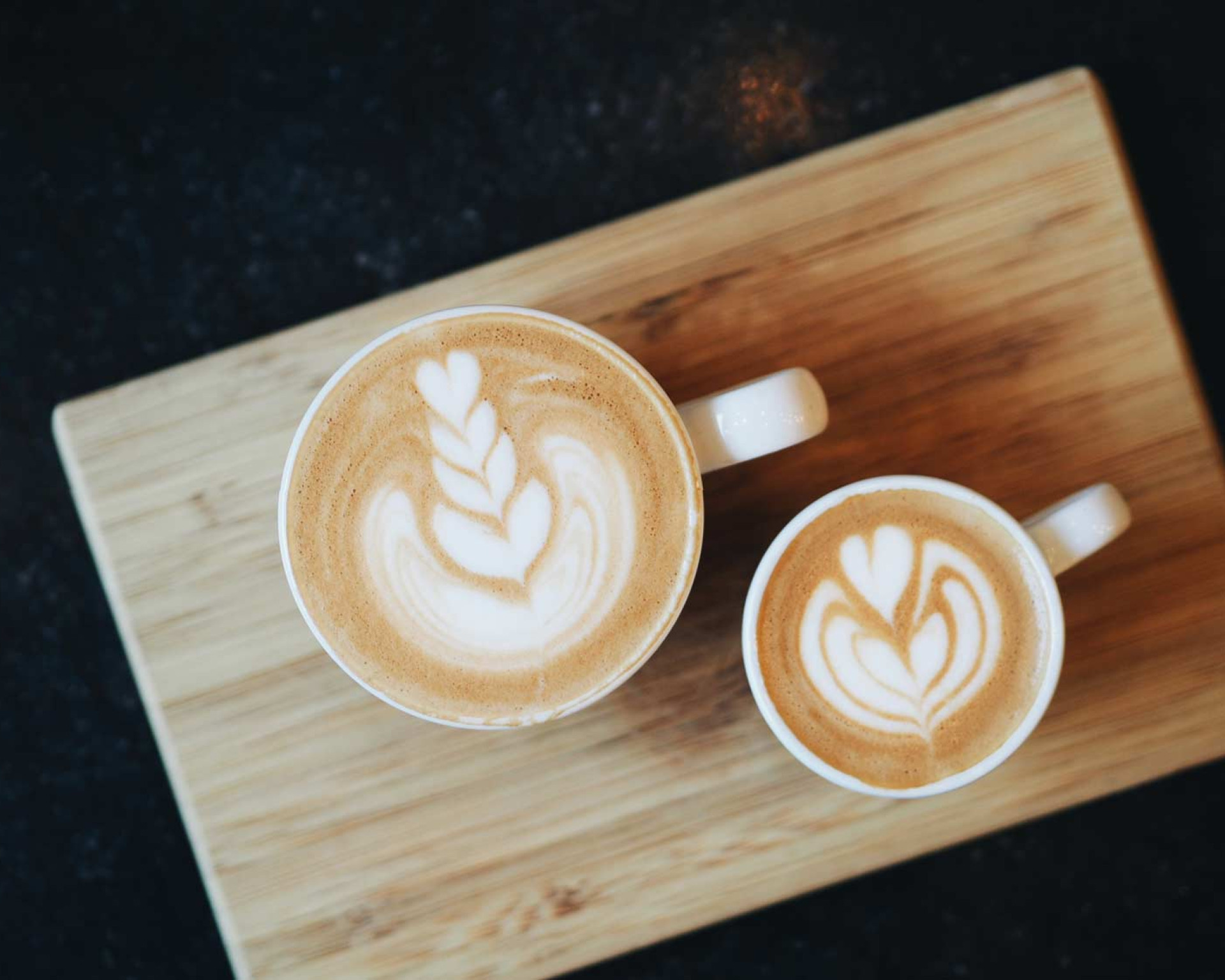 Twee cappucino's op een houten serveerplankje